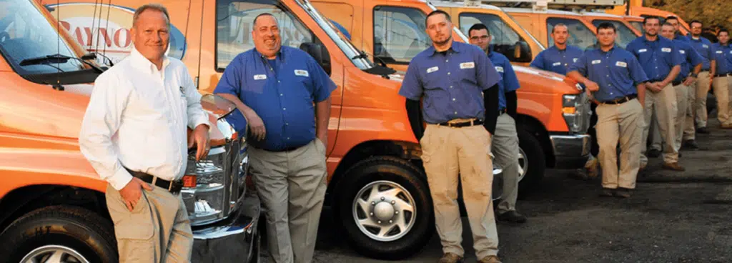 Raynor Services technicians in blue shirts standing infront of Raynor trucks