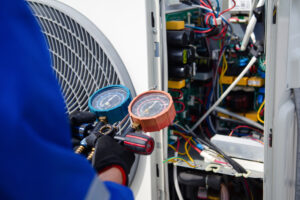 An air conditioner technician using a gauge to measure the refrigerant pressure